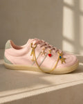 Pink sneaker close-up with gold starfish duo, red heart and chain shoe charm bundle