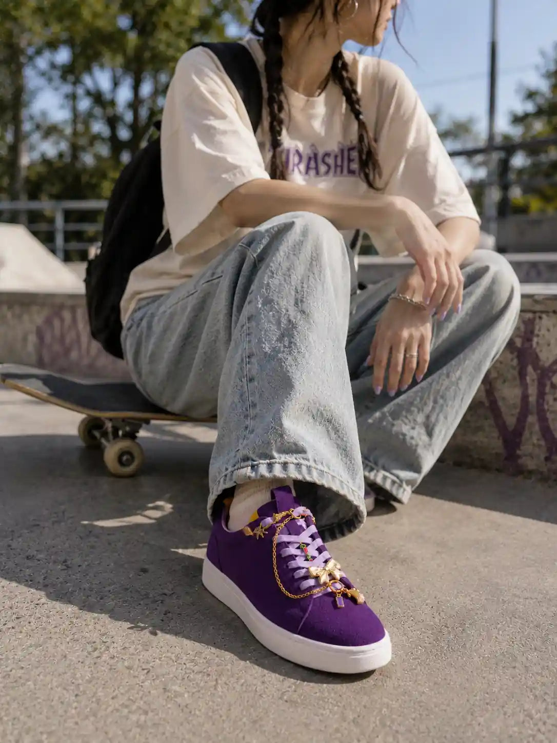 Person wearing a purple sneaker styled with the Bowtique Edit gold starfish chain, bow, rose, shell and gemstone shoe charms
