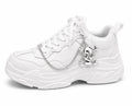 Silver skull shoe charm with chain attached to white sneaker