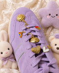 Close-up of a lavender sneaker with the Good Karma Edit gold sun, rainbow, striped heart, celestial and white heart charms
