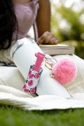 Rose Garden Glow Lip Balm Holder with floral print, pink pom pom and butterfly charm attached to a white tumbler