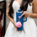Blue reusable bottle with pink pom pom charm and pink bunny straw accessory held by a woman