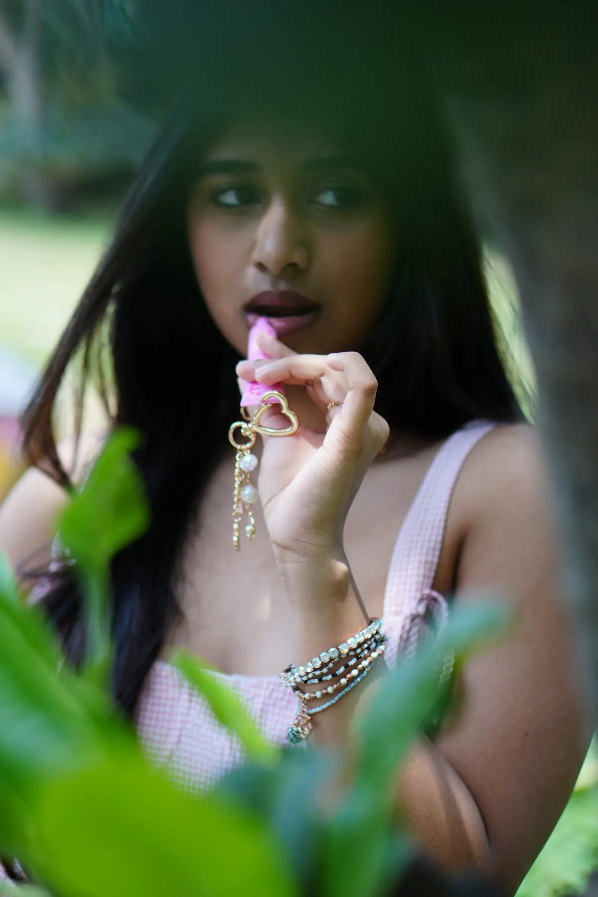 Woman using a pink lip balm with the blush pearl heart charm hanging from the tube