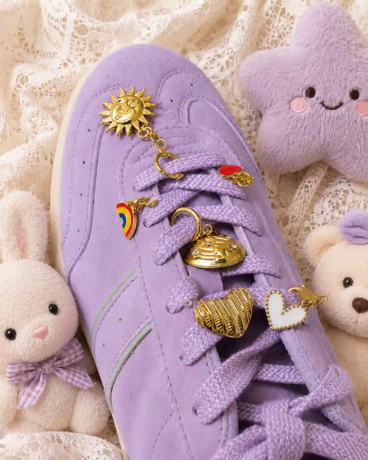 Close-up of a lavender sneaker with the Good Karma Edit gold sun, rainbow, striped heart, celestial and white heart charms