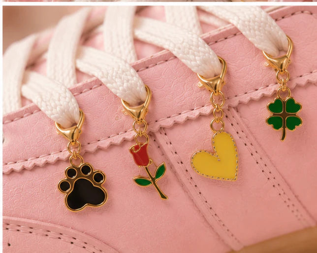 Close-up of Pawfect Match Edit gold paw print, rose, yellow heart and green clover charms on a pink sneaker