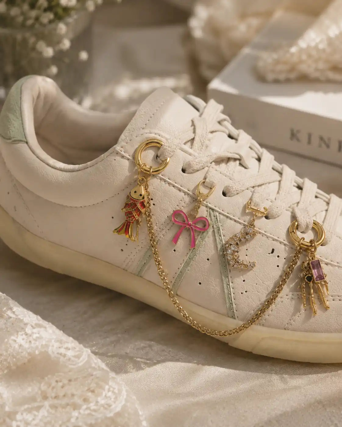White sneaker styled with the Pretty Please gold chain shoe charm bundle, featuring fish, bow, crystal moon and skeleton charms