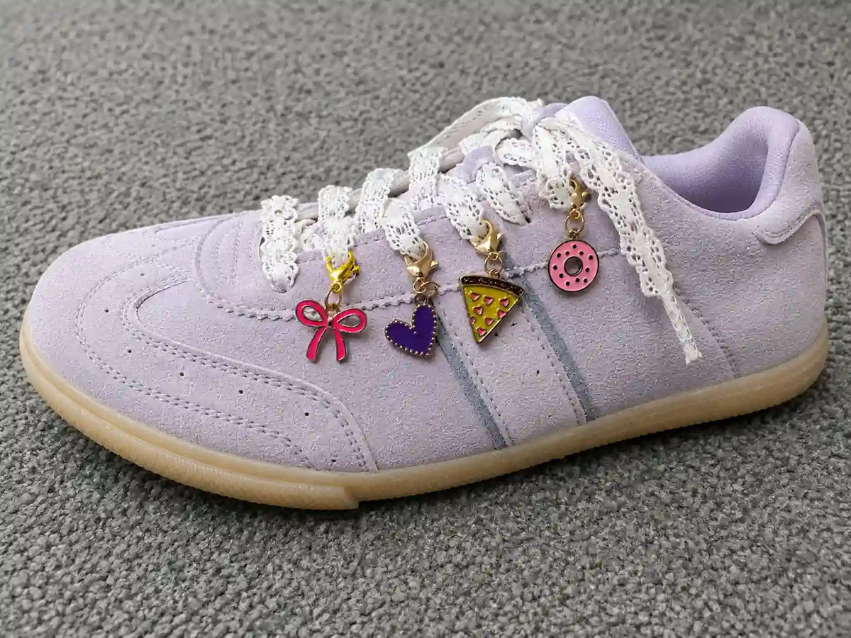 Lavender sneaker styled with the Slice Slice Baby Edit gold shoe charm bundle on a textured surface