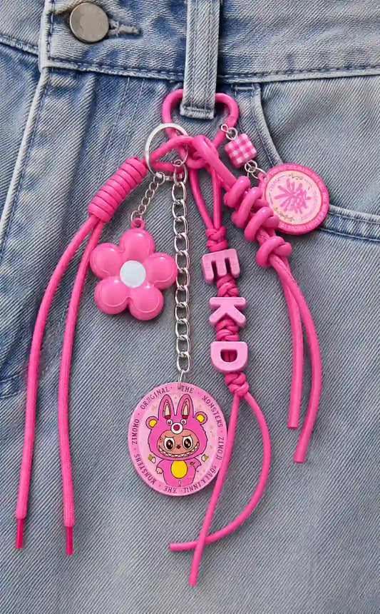 Pink Parade Floral Bag Charm styled on denim with pink flower, gingham accent, layered pink cords and character charm