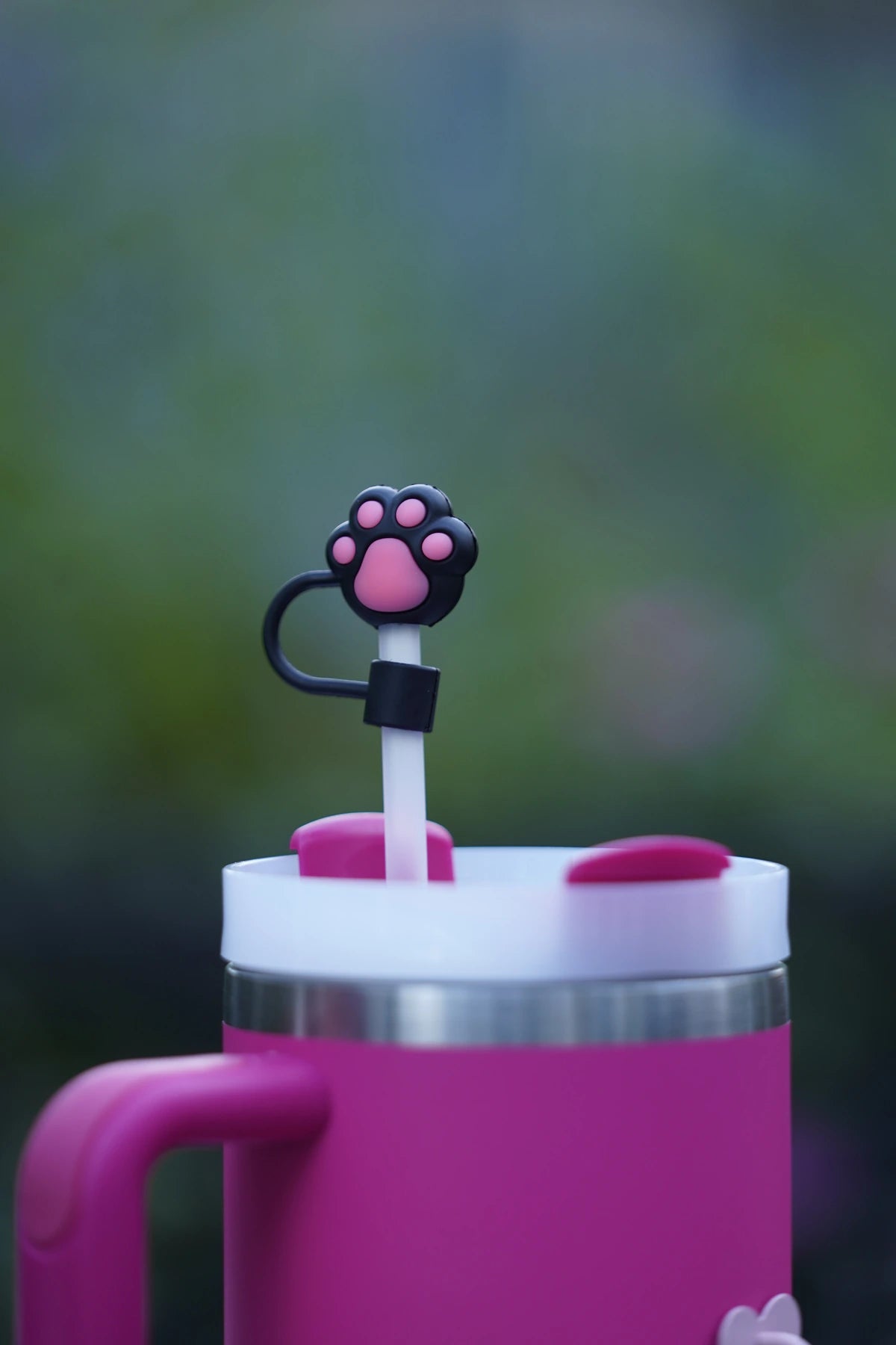 Pink paw print straw charm displayed on a pink tumbler with a white straw outdoors