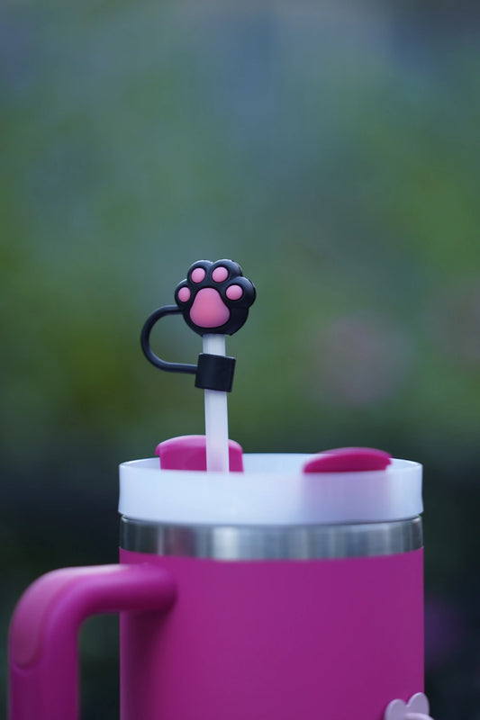 Pink paw print straw charm displayed on a pink tumbler with a white straw outdoors