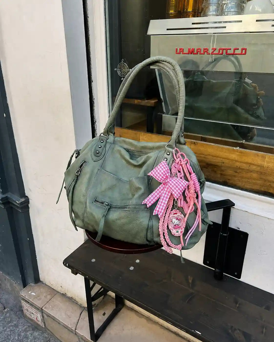 Pink gingham bow bag charm displayed on a grey handbag
