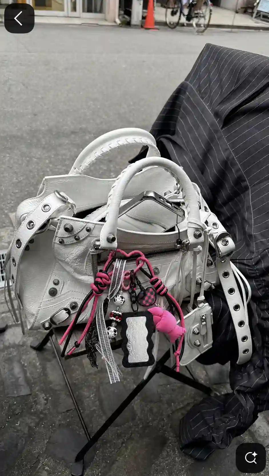White handbag styled with the Pink Rebel Drop pink-and-black cord and croissant bag charm