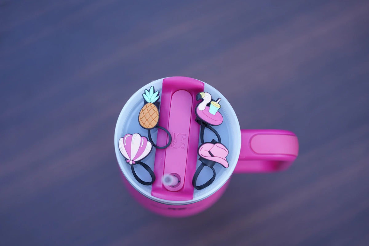 Four poolside-themed straw charms arranged on a pink tumbler lid