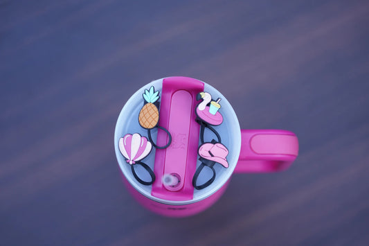 Four poolside-themed straw charms arranged on a pink tumbler lid