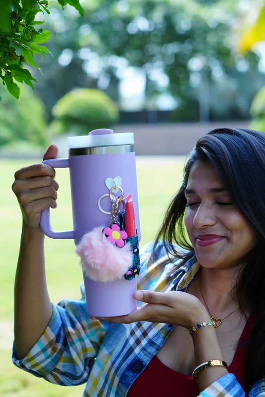 Woman holding a lavender tumbler decorated with a pink pom pom, tropical print lip balm holder and flower charm