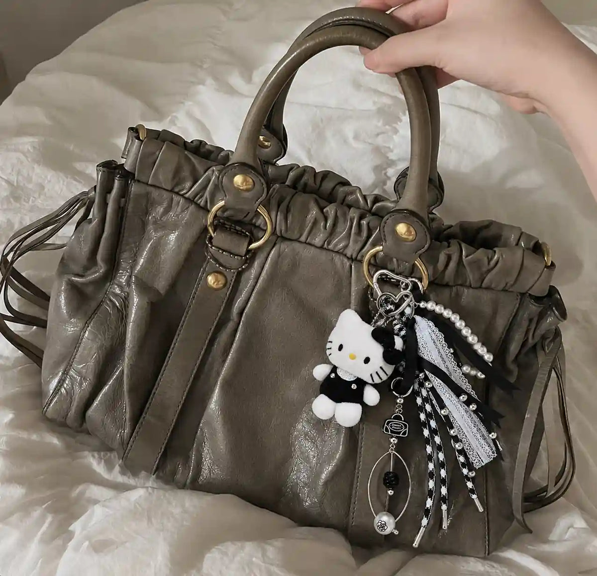 Soft Goth Kitty Bag Charm styled on a grey handbag with monochrome kitty, pearl strand, lace and black ribbons