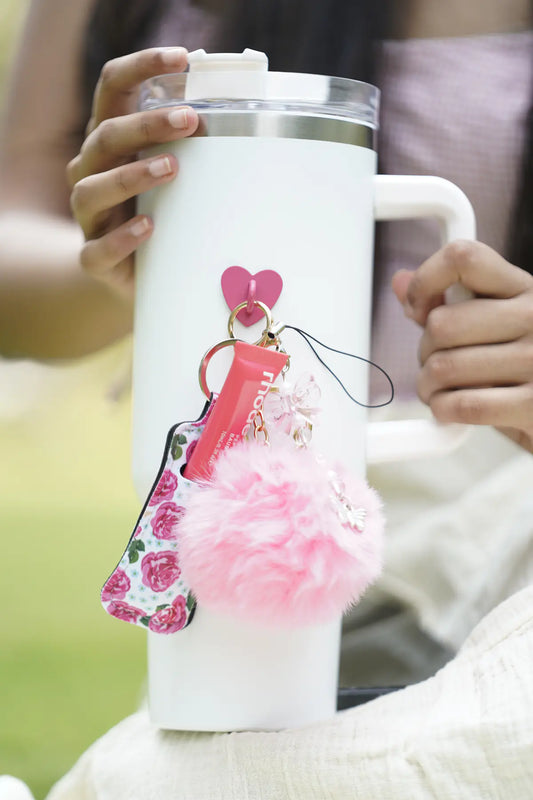 Rose Muse IT Girl Bundle attached to a white water bottle with pink pom pom, rose-print charm, lip balm holder and butterfly charm